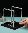 Five Ball Newton's Cradle Desk Toy For Gravity Demonstrations And Stress Relief, polished metal and plastic frame on desk