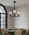 Industrial Glass Cylinder Pendant Chandelier in Black, 6 Light Farmhouse Vibe for Dining Room over a round table.