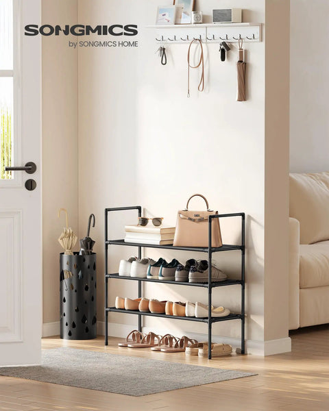 Three-Tier Shoe Rack Organizer For Hallways And Closets, Slim Space-Saving Metal Frame With Durable Non-Woven Fabric Shelves, Black Finish, Holds Up To 12 Pairs Of Shoes, Easy Assembly displayed in a hallway with shoes.