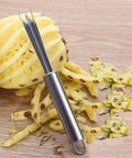 Pineapple Eye Remover And Core Cutter Tool V Shaped Stainless Steel Kitchen Gadget next to a partially peeled pineapple