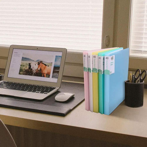 Desk with laptop, pen holder, and colorful 40-pocket binders, not 60 Pocket Portfolio Binder Organizer With Clear Sheet Protectors For 8.5 By 11 Inches Documents Holds 120 Pages Handy Office School Art And Concert Binder Pink Pro Grade Organization
