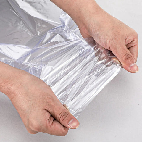Hands stretching clear POF film from Bulk 500 Pack Heat Shrink Wrap Bags For Packaging, showcasing material flexibility.