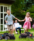 Kids playing with Dope Amphibious RC Monster Truck For Kids With Dual Batteries near a garden, two trucks in foreground.