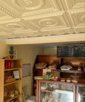 Laurel Wreath Faux Tin Ceiling Tiles White Pearl 25 Pack installed in a bakery, showing a classic tin look ceiling design.
