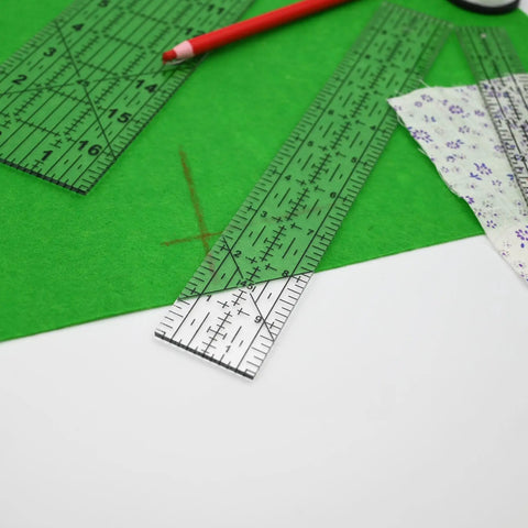 Dead Simple Acrylic Quilting Rulers And Nifty Fabric Cutting Templates For Patchwork Projects on green fabric with a red pencil.