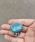 Totally Groovy Blue Mushroom Ceramic Cabinet Knobs, 6 Pack of Glossy Round Drawer Pulls for Dresser and Wardrobe, 1.38 Inch Diameter, Smooth Polish, 3 Screw Sizes Included held in hand.