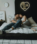 Couple in bed under a heart-shaped neon sign with wedding anniversary message, bedroom decor.