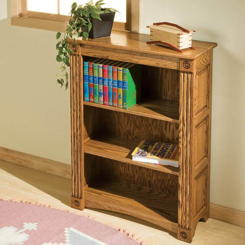 Wooden bookshelf in room with books and decor on top, located near window on light wood flooring.