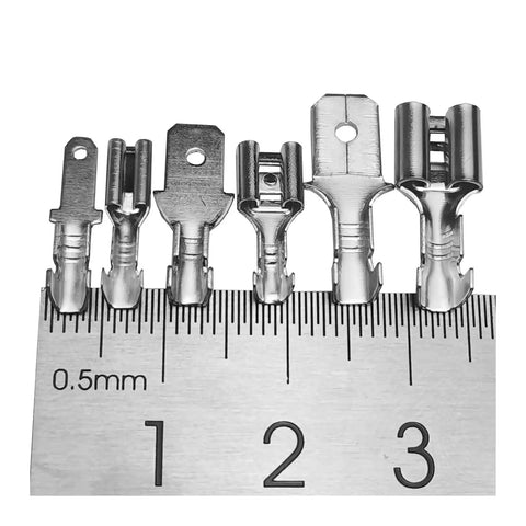 Solid Brass Tinned Spade Crimp Terminals Kit For Quick Wire Connections In Audio And Home Appliances, 2.8mm 4.8mm and 6.3mm Female Male Pins Compatible With 14-18 AWG Wiring For Solid Hookups. Metal terminals lined up on a ruler