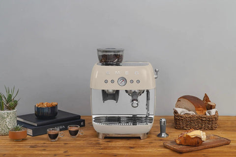 Top Shelf Semi Automatic Espresso Machine With Built In Conical Burr Grinder Dual Thermoblock Heating Precision Controls And Authentic 1950s Retro Vibe In Smooth Cream Finish on wooden table with coffee.