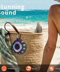 Waterproof Shower Bluetooth Speaker With IPX7 Rating hangs from a beach bag, showing carabiner and LED lights beside person on beach.