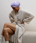 Woman wearing a marble pattern reusable waterproof shower cap with nonslip silicone forehead strip in a relaxed pose