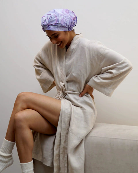 Woman wearing a marble pattern reusable waterproof shower cap with nonslip silicone forehead strip in a relaxed pose