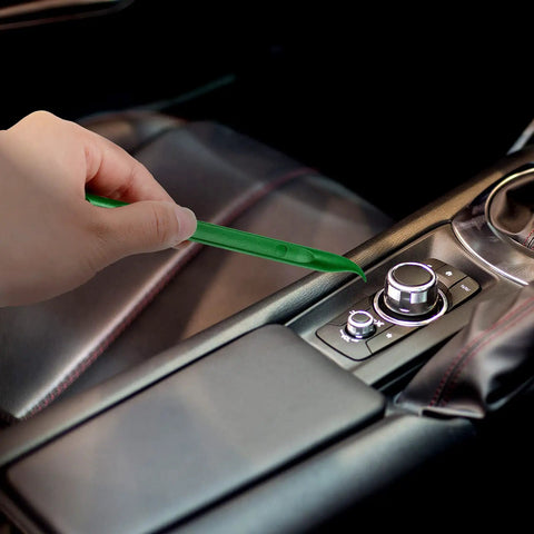 Using Nine Piece Plastic Scraper Tool Set for scratch-free cleaning of car console crevices, non-scratch green scraper shown