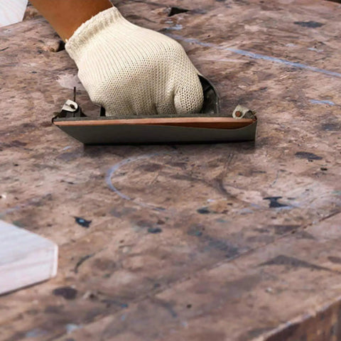 Hand using Pro Grade 25 Piece Sandpaper Set For Wet Dry Sanding With Grit Levels 1000 2000 3000 5000 7000 on a wooden surface