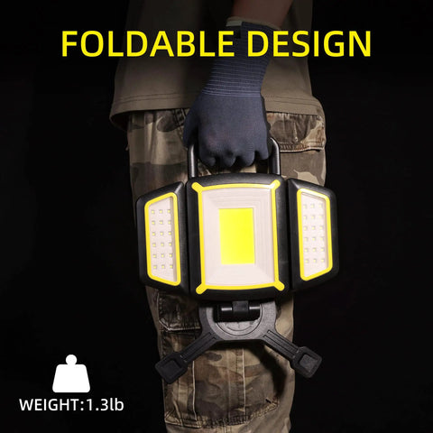 Person holding Rechargeable 30W LED Work Light with foldable design and magnetic base in a workshop setting.