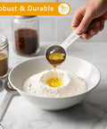 Pouring oil into flour using Six Piece Stainless Steel Measuring Spoons Set For Cooking And Baking Includes One Eighth Teaspoon One Quarter Teaspoon One Half Teaspoon One Teaspoon One Half Tablespoon One Tablespoon Coffee Scoop Rust Resistant Food Grade Kitchen Gadgets
