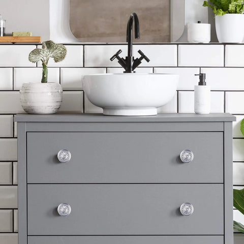 Gray dresser with 4 Pack Brushed Nickel Cabinet Hardware Knobs, 1.4 Inch Round Drawer Pulls For Cabinets And Dressers, in bathroom setting.