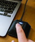 Person using AC 44TAP USB Boundary Conferencing Microphone With Capacitive Touch Mute Toggle next to laptop on wooden desk