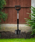 Heavy Duty 31 Inch Shovel With D Handle For Camping And Digging, Tough Steel Spade For Edging And Quick Work, Lightweight Yet Strong Metal Tool In Black standing upright in a garden setting, showing black spade and handle.