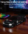 Black 1 To 64 Scale Mini RC Drift Car With LED Lights on wooden desk, computer and keyboard in background, emphasizing indoor use