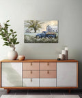 Blue Truck Canvas Wall Art With White Floral Accents, Retro Old Barn Pickup Truck Print For Farmhouse Decor, 18 By 24 Inches displayed above a modern wooden console in a living room setting.
