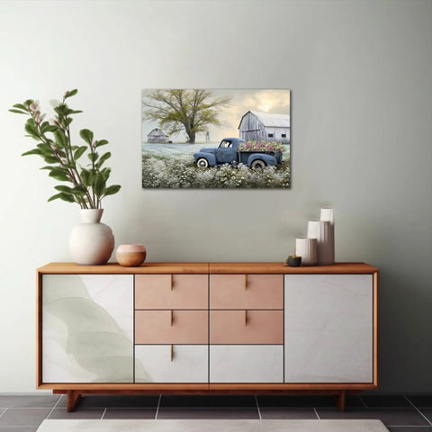 Blue Truck Canvas Wall Art With White Floral Accents, Retro Old Barn Pickup Truck Print For Farmhouse Decor, 18 By 24 Inches displayed above a modern wooden console in a living room setting.