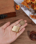 Hand holding brass habaki collar clip for swords with vintage golden finish, next to coin for size comparison