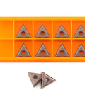 Ten TNMG carbide turning inserts in orange organizer tray for CNC lathes.