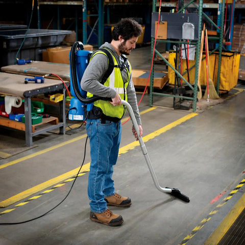 Person using Ergonomic HEPA Backpack Vacuum With 8 Piece Tool Kit 2.5 Gallon Capacity 105 CFM 1080W 120V in warehouse