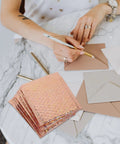 Rose Metallic Padded Mailers 20 Pack 6x5 Inch Self Sealing Cushioned Shipping Bags on marble table with envelopes