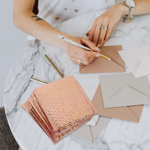 Rose Metallic Padded Mailers 20 Pack 6x5 Inch Self Sealing Cushioned Shipping Bags on marble table with envelopes