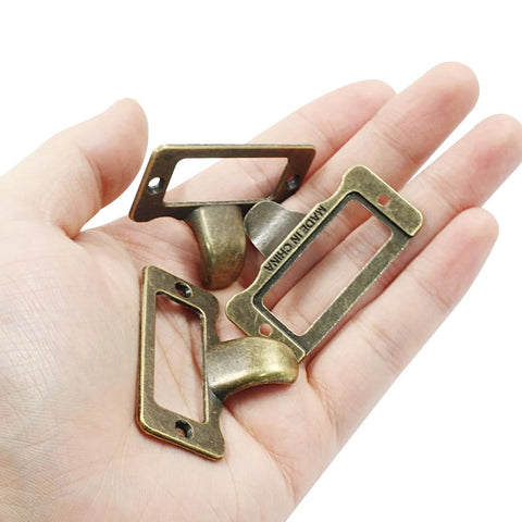 Close-up of vintage antique bronze label pulls for card catalogs and library drawers, 10 pack with screws in hand.