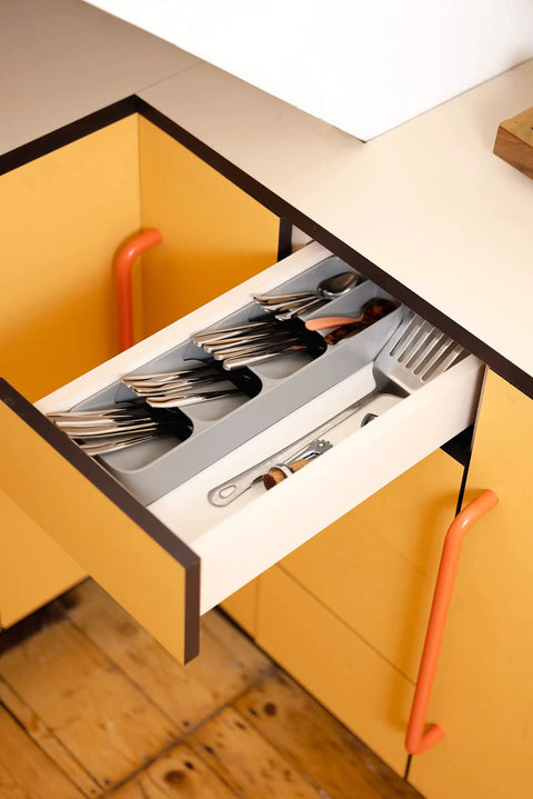 Slick And Dead Simple Kitchen Drawer Organizer Tray With Stackable Compartments For Killer Silverware Sorting And No Sweat Flatware Storage Setup In Sleek Grey with fork and spoon visible in drawer.