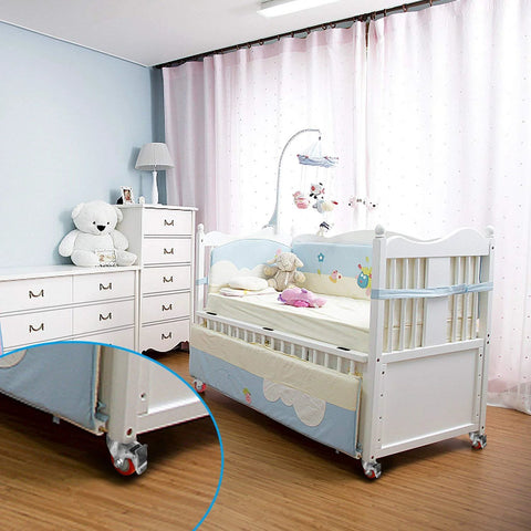 PRITEK 5-inch plate caster wheels, 4-pack with brakes on a white baby crib; red wheel hubs (front view).