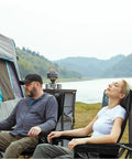 Two people relaxing in Oversized Folding Camping Chair With High Back Support 500 Lbs Capacity by a tent and lake.