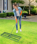 Person using Heavy Duty Lawn Leveling Rake With 180 Degree Adjustable Head And 5.74 Feet Long Handle For Your Yard Backyards Gardens Farms Lawns Rust Resistant Steel Tool For Easy Smoothing And Leveling Of Uneven Soil on a green lawn