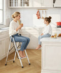 3 Step Aluminum Step Ladder Foldable For Home Use With Steel Frame Stable No Wobble Design Rust Resistant Coating 330 Lb Capacity Lightweight Yet Durable Perfect For Indoor Tasks And Quick Outdoor Fixes. Woman using 3-step aluminum ladder in kitchen