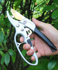 Ratcheting Garden Pruners For Easy Pruning Of Roses Flowers Hedges And Trees With Germany Titanium Blades in hand near leaves