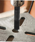 Close-up of hydraulic tool kit with punch driver and die set punching a hole in metal sheet for electrical conduit projects.