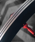 Close-up of red alloy tubeless Presta valve stem installed in a bicycle wheel rim.