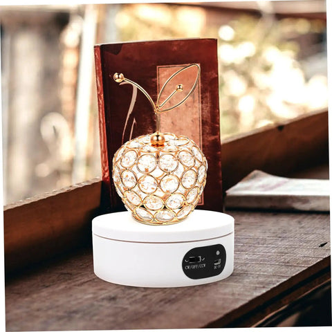 Luxshiny Electric Jewelry Rotating Turntable Display Stand With Smooth Auto-Spin Action For Storefronts And Home Organization Stylish Acrylic Showcase Rack showcasing a crystal apple on a white base.