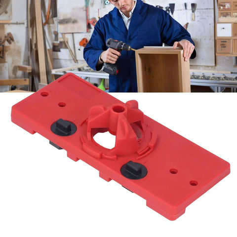Red plastic woodworking hinge drilling jig for 35mm holes; two black adjustment knobs