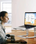 Aluminum Laptop Stand With 6 Inch Elevation, Ergonomic Detachable Notebook Riser, Silver, holding a laptop on a desk with a person using it.