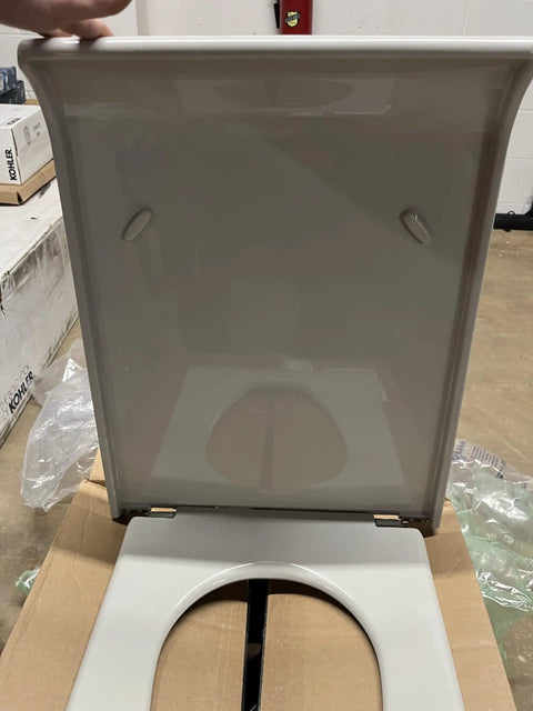 Slick Pillow Talk Toilet Seat In Clean Ice Grey Featuring Smooth Soft Close Hinges, top loading mount design on cardboard.