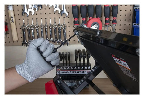 Cool Star Shaped T Handle Hex Key Tool Set For Metric And Imperial Sizes Perfect For Vehicle Maintenance Or DIY House Repairs With Strong Grip To Loosen Tight Fasteners Easily Without Breaking A Sweat., gloved hand using black T-handle hex key on metal frame