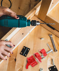 Person using drill next to lightweight one half inch quick release pipe clamp for woodworking red carpenter clamp and tools.