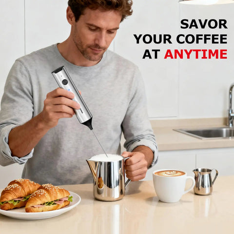 Man using Rechargeable Milk Frother With Stand 3 Speed Handheld Electric Wand Mixer For Matcha Lattes And Cappuccinos Dual Spring Whisk USB C Fast Charge Kitchen Must Have Gift For Home Baristas next to croissants and coffee on kitchen counter.