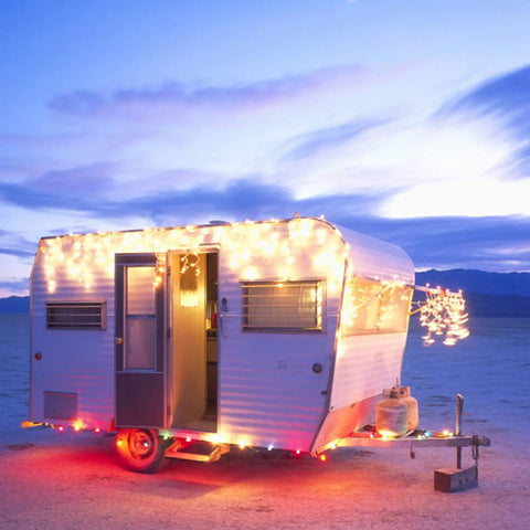 100 Count Mini Clear Christmas Lights On 21 Feet White Wire For Indoor Outdoor Decor lit up along camper at sunset.