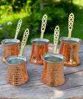 Handcrafted Copper Turkish Coffee Maker With Five Pots on wooden surface outdoors